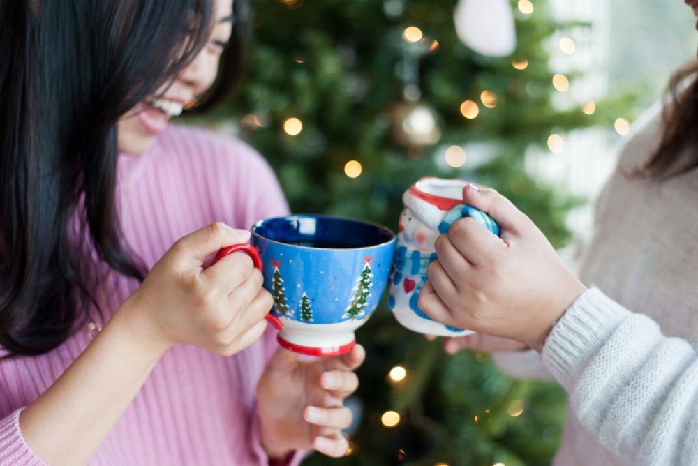 Friends with Christmas and holiday mugs cheers with Sips by tea