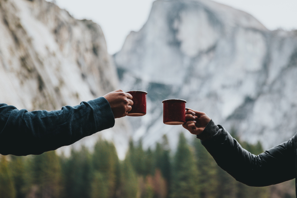 Two people in front of a mountain holding out cups of ethical tea