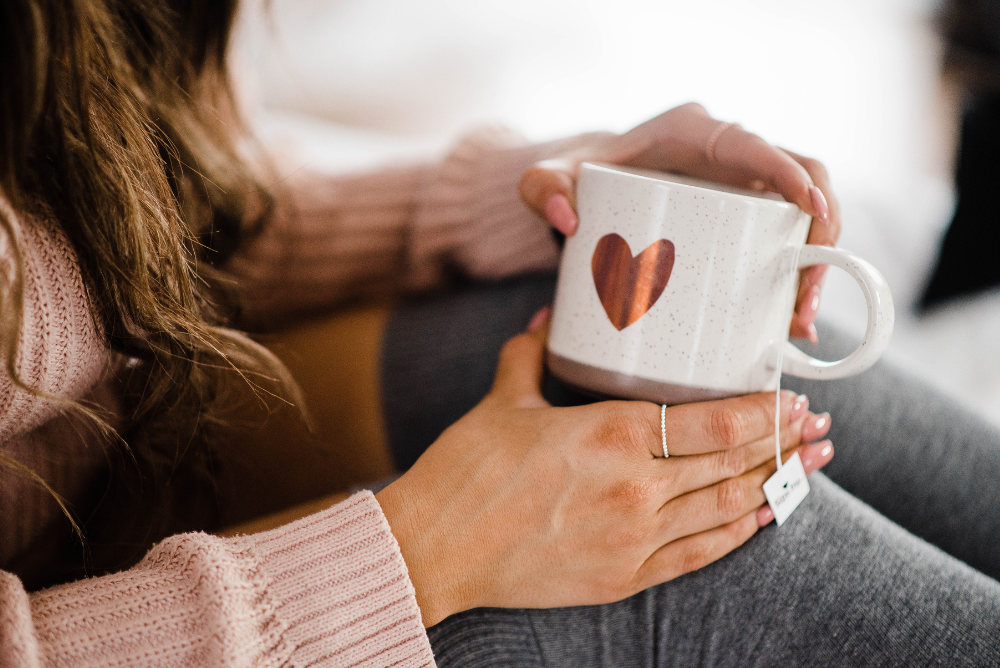 Person holding a white mug with a red heart