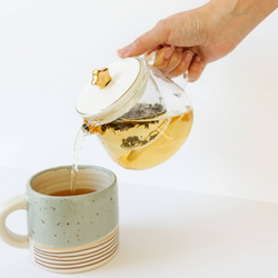 Sips by glass galaxy teapot with star lid pouring tea into ceramic mug