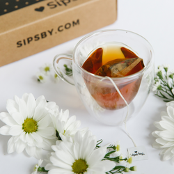 Cup of chamomile tea with Sips by box and flowers