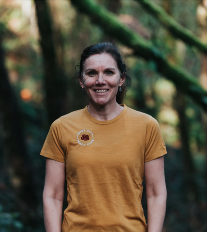 Emma, a Rose City Track Club member, wearing a yellow club shirt posing for a photo