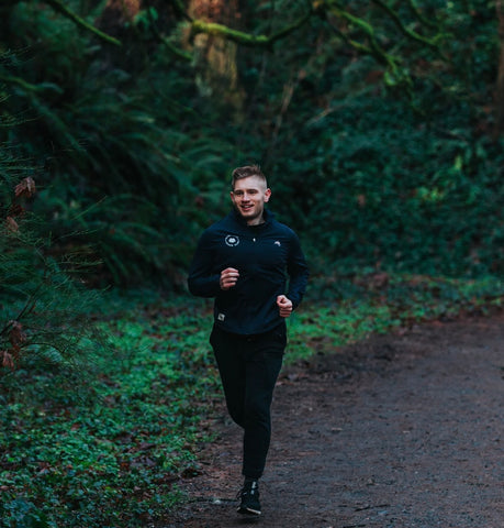 Ryan Yambra, a Rose City Track Club member, jogging down a damp forest trail
