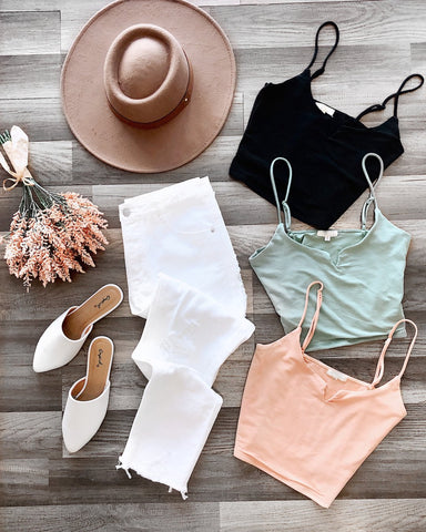 Assortment of crop tops, white jeans, white flats, and beige hat
