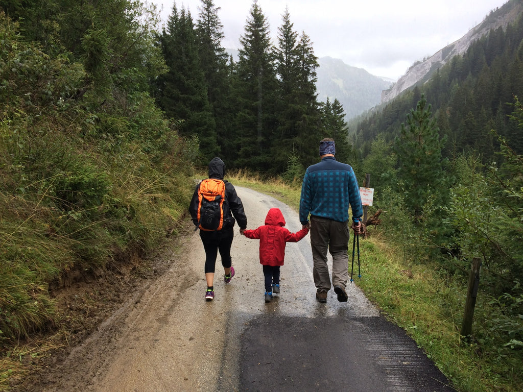 family of three walking taking a hike in a green forest