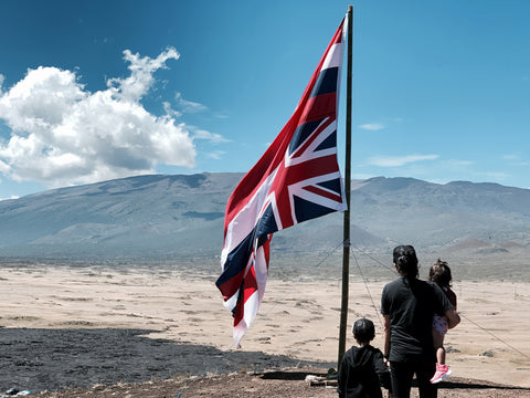 mom and two kids looking at mauna kea by a Hawaiian flag