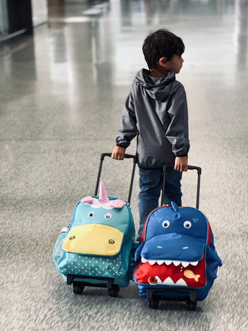 toddler wheeling two toddler suitcases at the airport