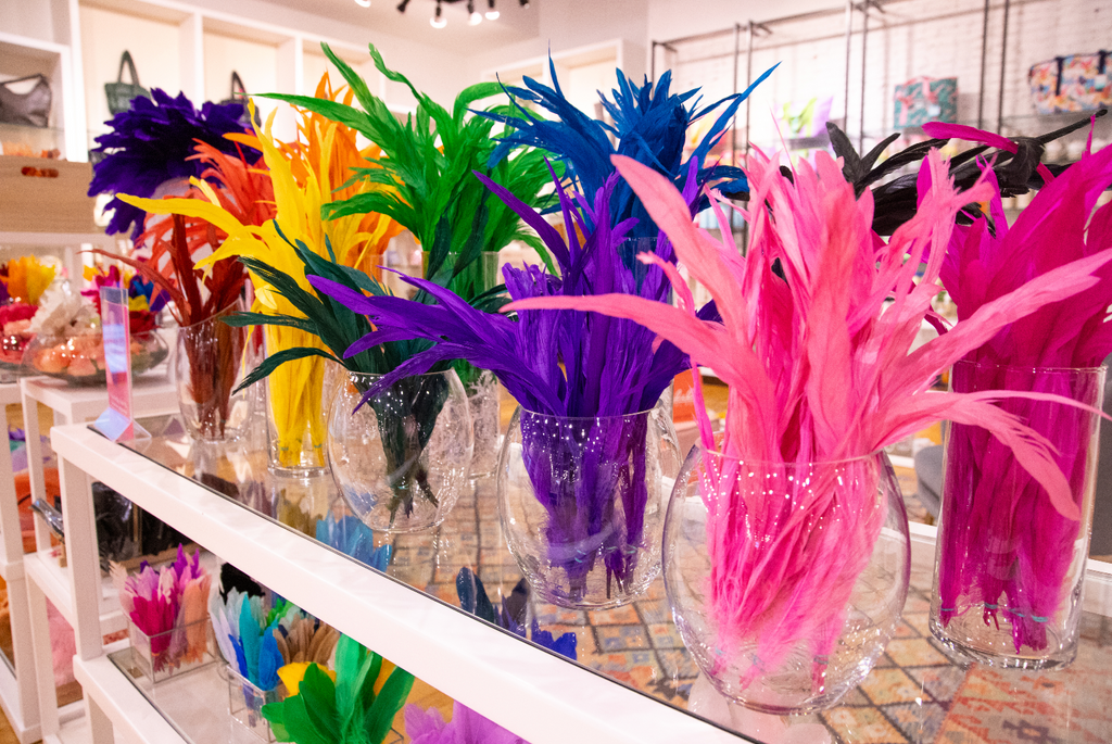 Different colors of feathers hosted in separate glass vases for the creation of a DIY fascinator