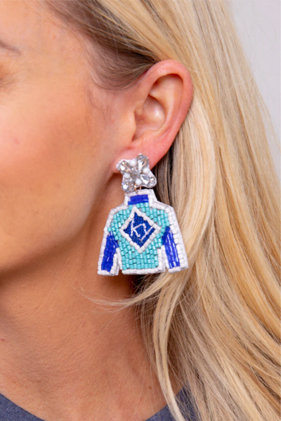A blonde woman wearing an earring that shows a jockey silk.