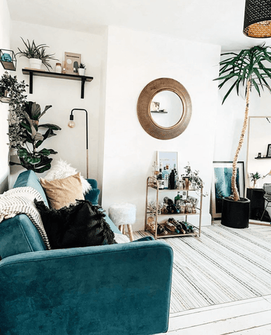 A stunning teal sofa and plenty of houseplants add a fresh pop of colour to the living area, while the drinks trolley gives it a modern edge