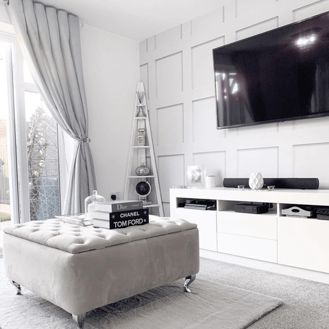 Corner shelving and paneling add a stylish touch to the living room, along with a rather splendid upholstered foot stool.