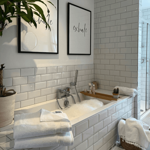 Classic white metro tiles surround the walk-in shower and bath tub, which feature a stack of Hampton and Astley indulgently thick bath sheets.