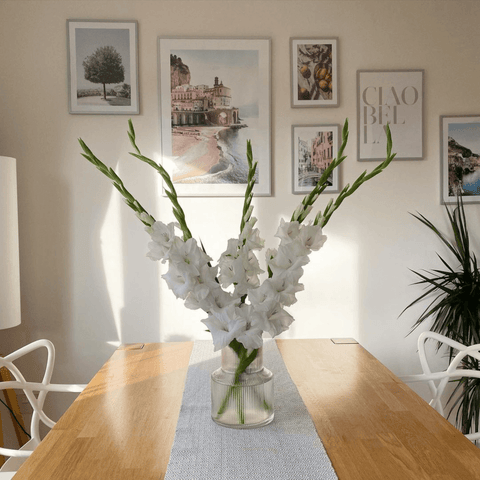 A vase of white gladioli adds a fresh vibe to the oak dining table.