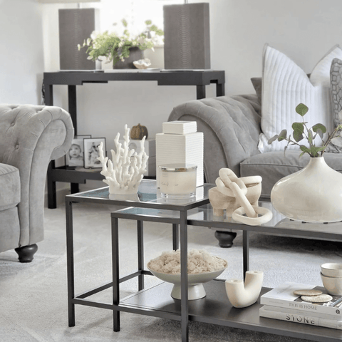 Nested glass coffee tables with white ornaments provide a visual focal point.