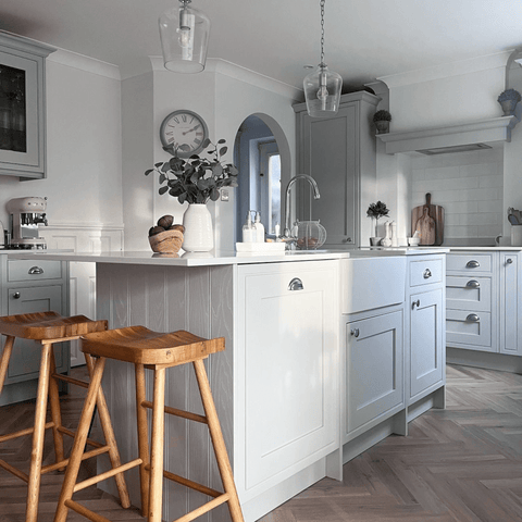Light grey shaker-style units are topped wit simple white worktops in this stunning kitchen.