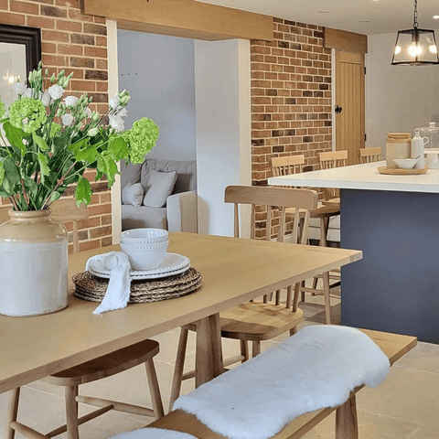 The modern cottage kitchen features exposed brickwork, oak beams and rustic wood doors.