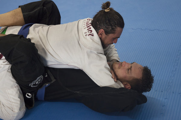 White, with no posture or available arms to post, attempts a choke from inside the guard