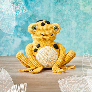 A crocheted yellow frog with pale belly and brown spots