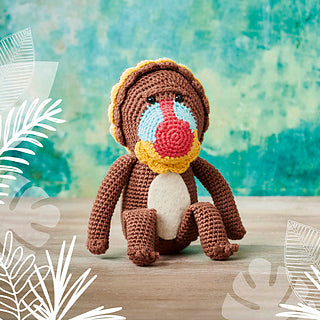 A crochet mandril - a brown monkey with blue face and red nose