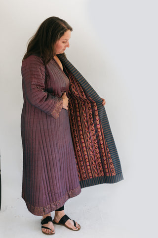 Quilted turkish coat held open by a woman wearing it in front of a white screen.