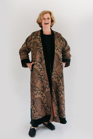 Woman standing with hands in side slits on turkish coat made with a heavy jacquard fabric.