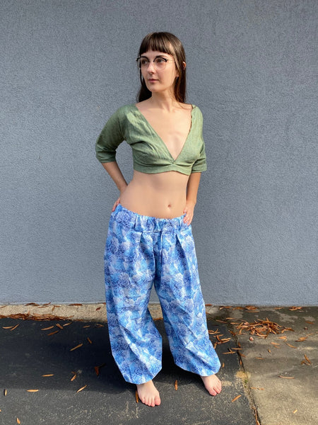 barefoot woman with long brown hair standing in front of grey wall with green crop choli top and blue print pantaloons.