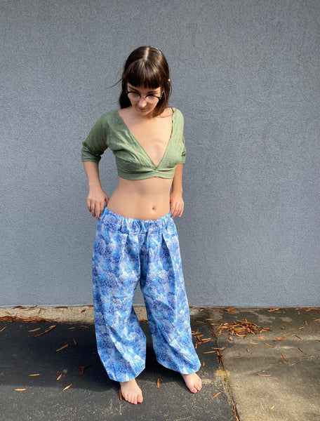 barefoot woman with long brown hair standing in front of grey wall with green crop choli top and blue print pantaloons.