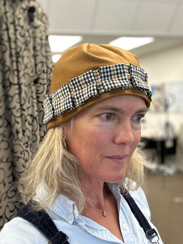 Woman in a brown hat with a black and white band and a blue shirt.