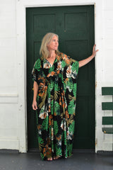 woman standing in a doorway of a green door wearing a green tropical print kaftan