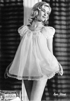 Black and white image of a woman wearing a sheer baby doll lingerie dress with short cap sleeves.