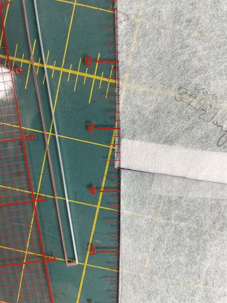 clear hip curve ruler next to tracing fabric on a cutting mat