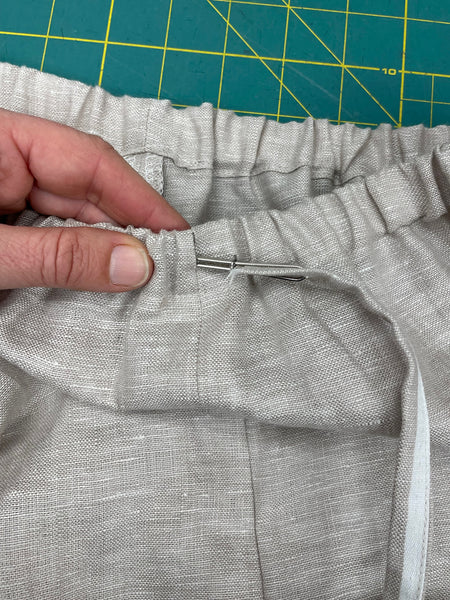 drawstring being fed through front opening of pants