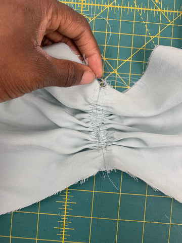 Close up of Gathered Center Front of Bodice Front A held by an African American hand on a green cutting mat.