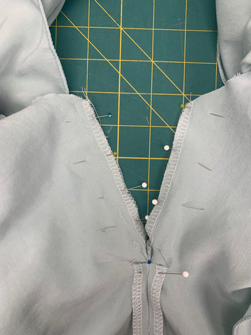 Close up of pinned upper skirt to wrong side of lower skirt at center back seam between dot and waistline on a green cutting mat
