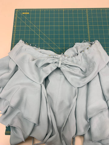 Pinned finished skirts to finished bodice at waistline laid out on a green cutting mat.