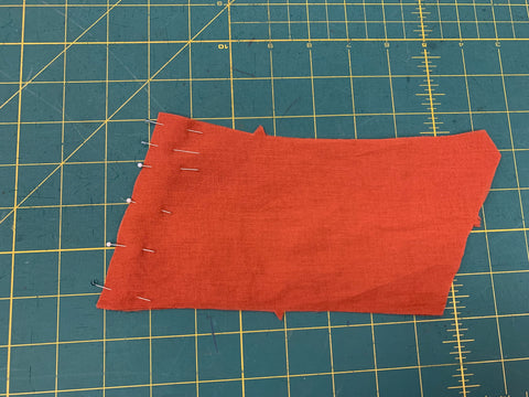 Back Pieces in Orange pinned right sides together on a green cutting mat.