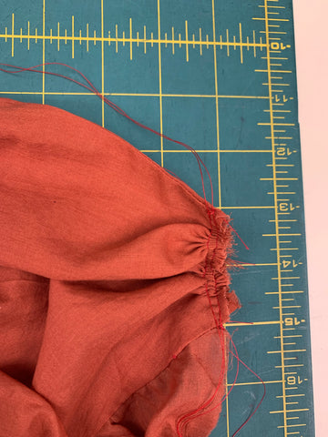 Pulled gathering threads till orange center front of Bodice A measures 2” (5cm), on a green cutting mat.