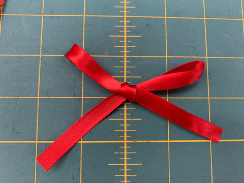 A red ribbon bow on a green cutting mat