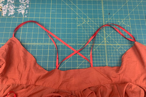 All red ribbon straps sewn on the back bodice in a crisscross layout laying on a green cutting mat