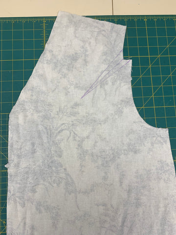 Dart is marked on left bodice with purple chalk on the wrong side of fabric places on a green cutting mat.