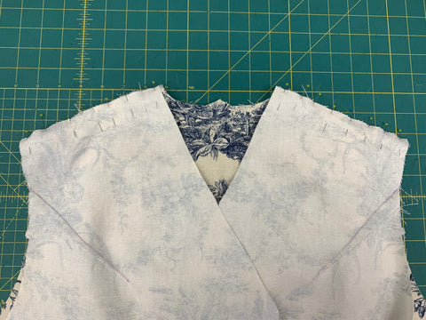 Pinned front and back pieces wrong sides together at the shoulder on a green cutting mat.