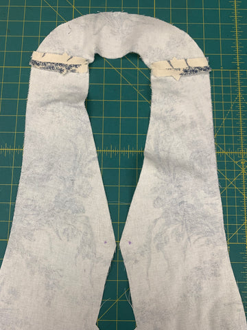 Sewn right sides together neck and front facings with seams pressed open on a green cutting mat.