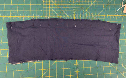 Pinned navy blue cuff right sides together to lining on a green cutting mat.