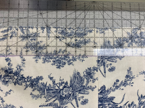 Marking a three inch line from the raw edge of the hem with a clear ruler on a french toile cotton canvas fabric.