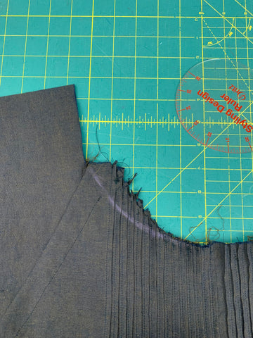 Purple chalk line from the center of the bodice to the sleeve and facing seam line. on a green cutting mat.