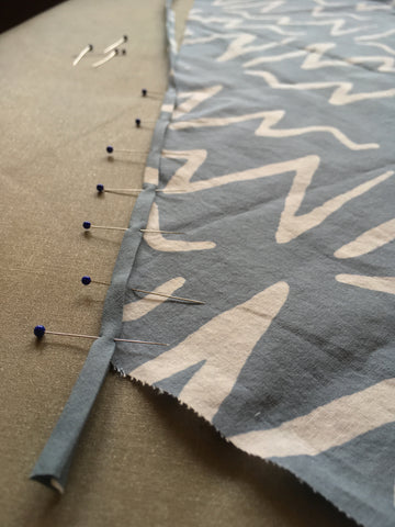 Phot of bias tape and fabric pinned together at raw edge
