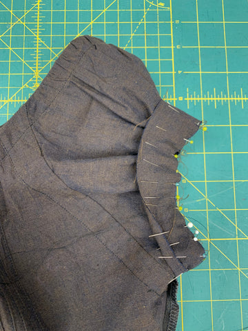 Wrong sides together pinned sleeve band F to bottom edge of sleeve on a green cutting mat.