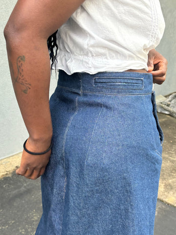 Close up of the darts on the denim sailor skirt worn by an African American woman.