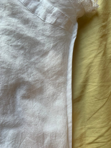 White cotton voile fabric french seam for the side seam of the garment, on a pale yellow background.