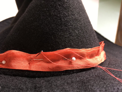 Photo of hand stitching the ribbon to the hat